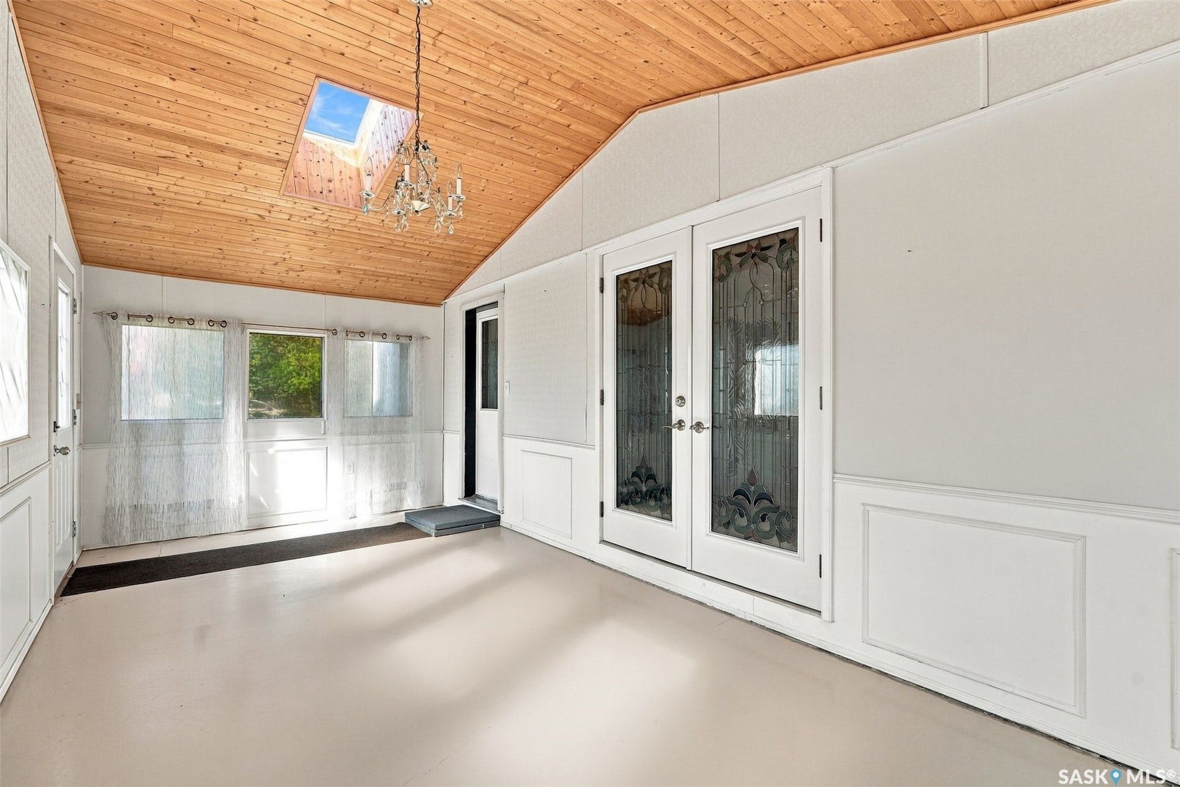 Wood-paneled vaulted ceiling with a central skylight and chandelier