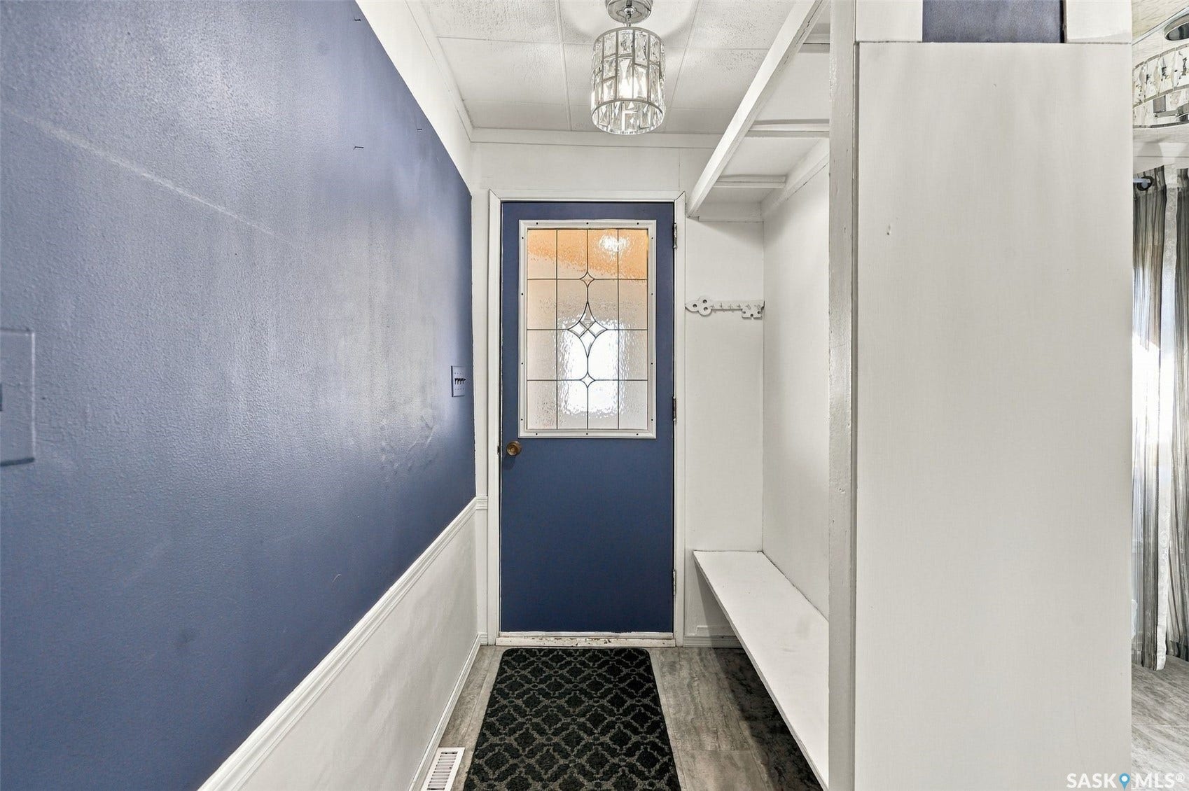 Entryway featuring a decorative glass panel door, built-in bench with storage, coat hooks, and wood-finish flooring