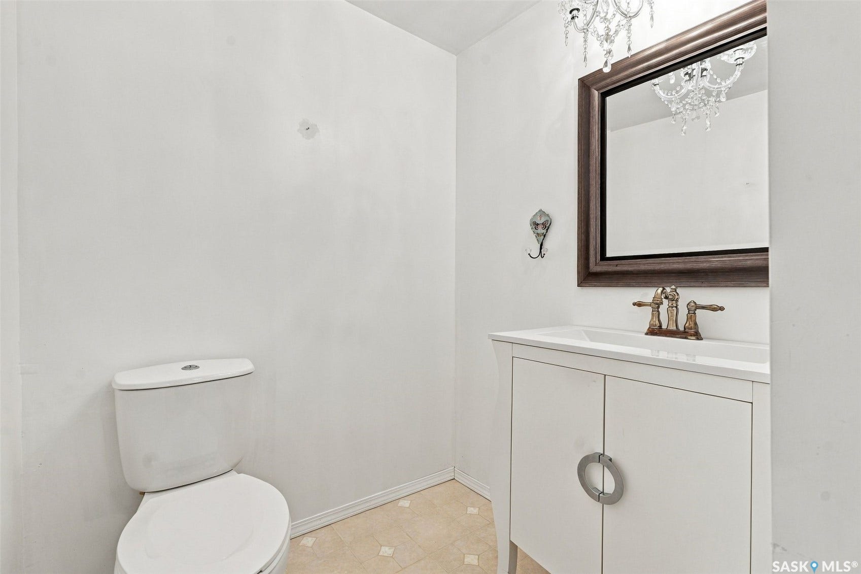White vanity with circular hardware, undermount sink, and a rectangular mirror with a dark wood frame