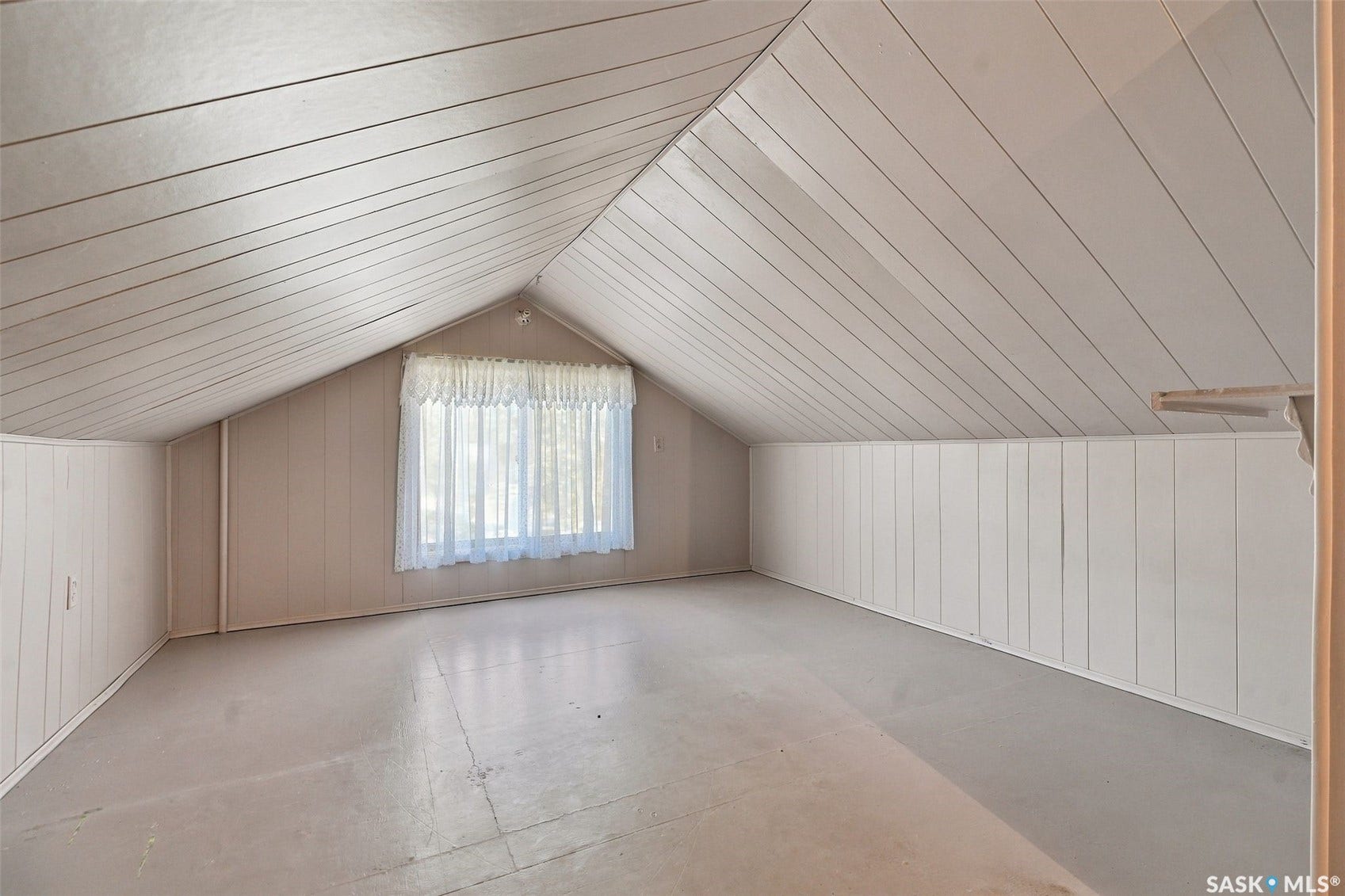 Room with sloped ceilings featuring horizontal paneling and a large window