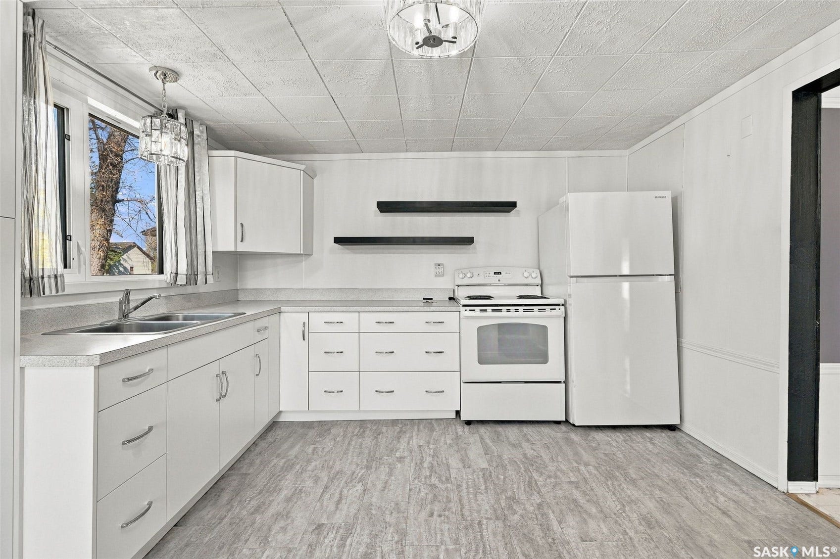 White cabinetry with chrome hardware, dual basin stainless steel sink, white range, white refrigerator, and wood-finish flooring