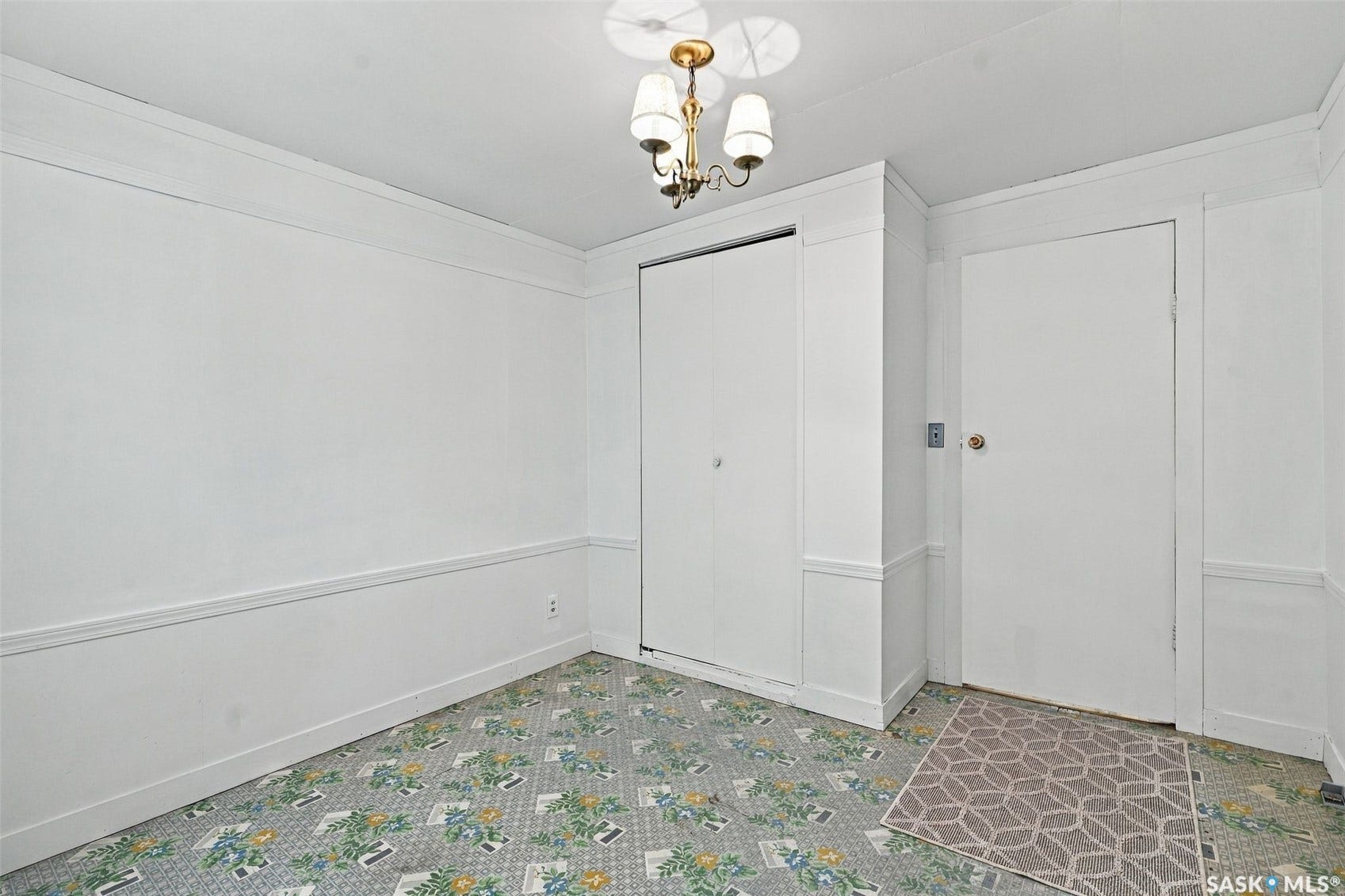 Interior space featuring a ceiling-mounted light fixture, white walls, and a patterned floor covering