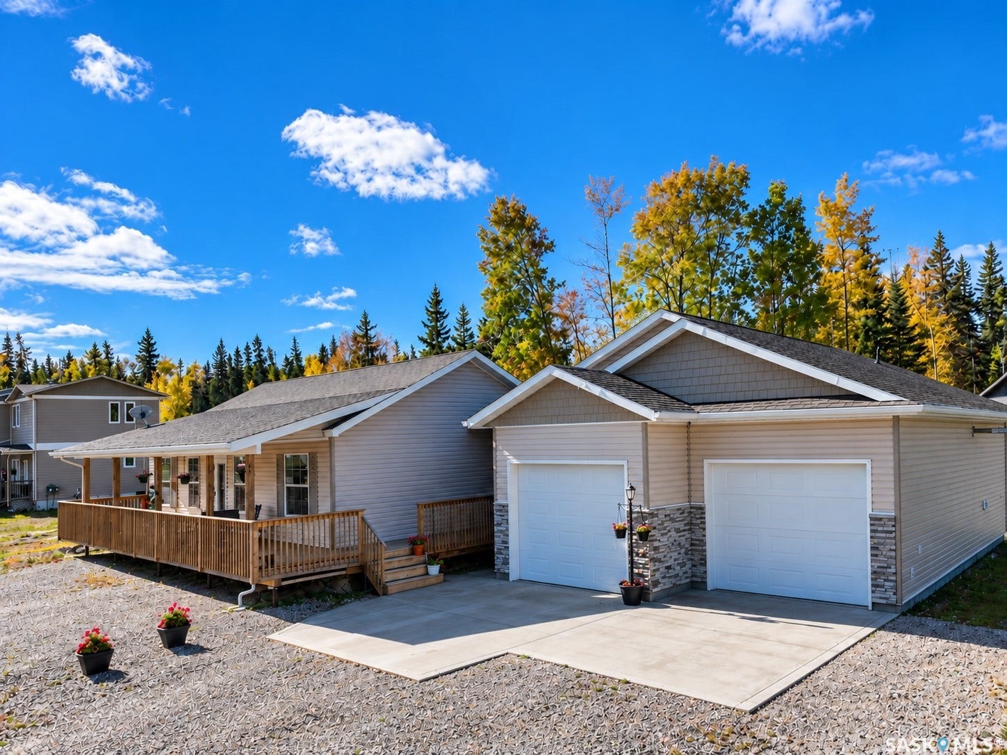 Exterior featuring light-colored siding, a concrete driveway, a wood-finish deck, and stone accents