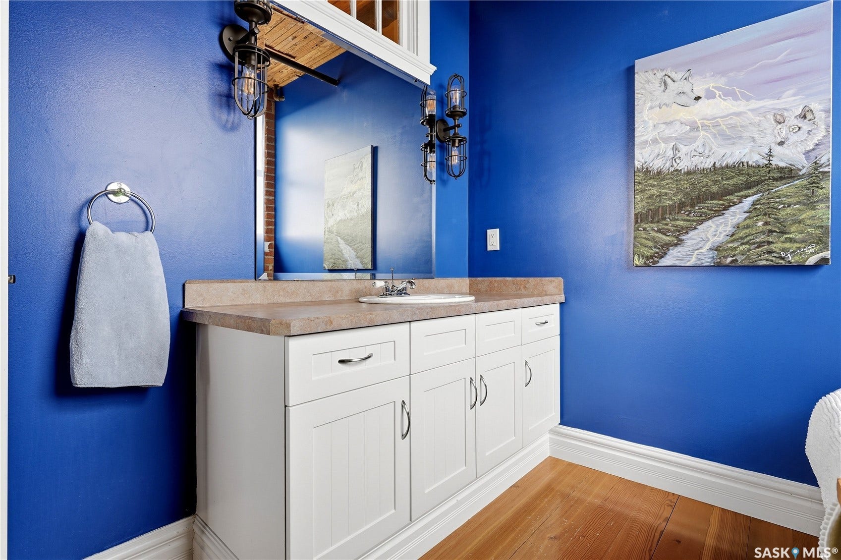 White vanity with beadboard door panels, a single basin sink, and a countertop