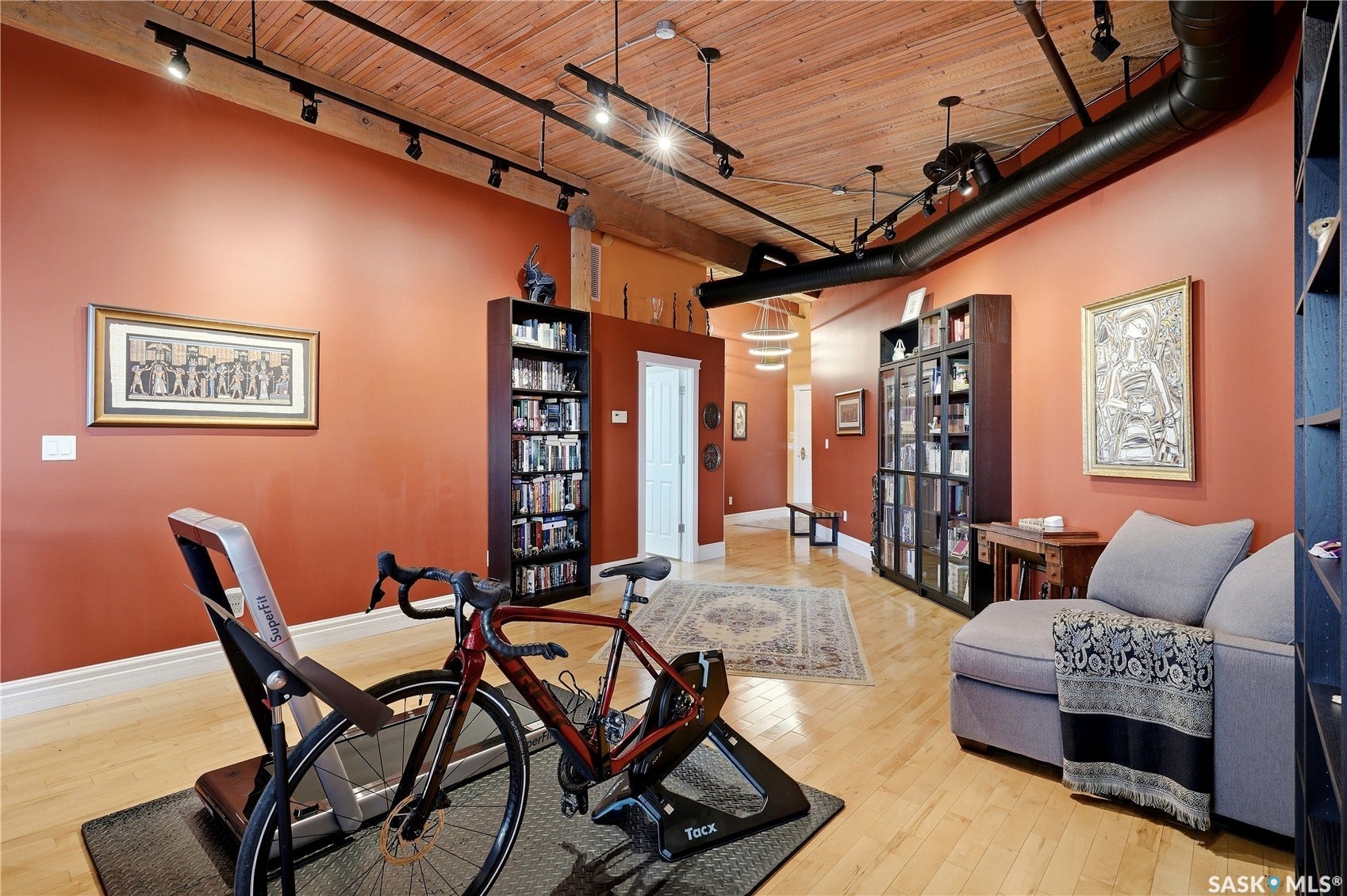 Exposed ductwork, track lighting, wood-finish flooring, built-in shelving, and a wood plank ceiling