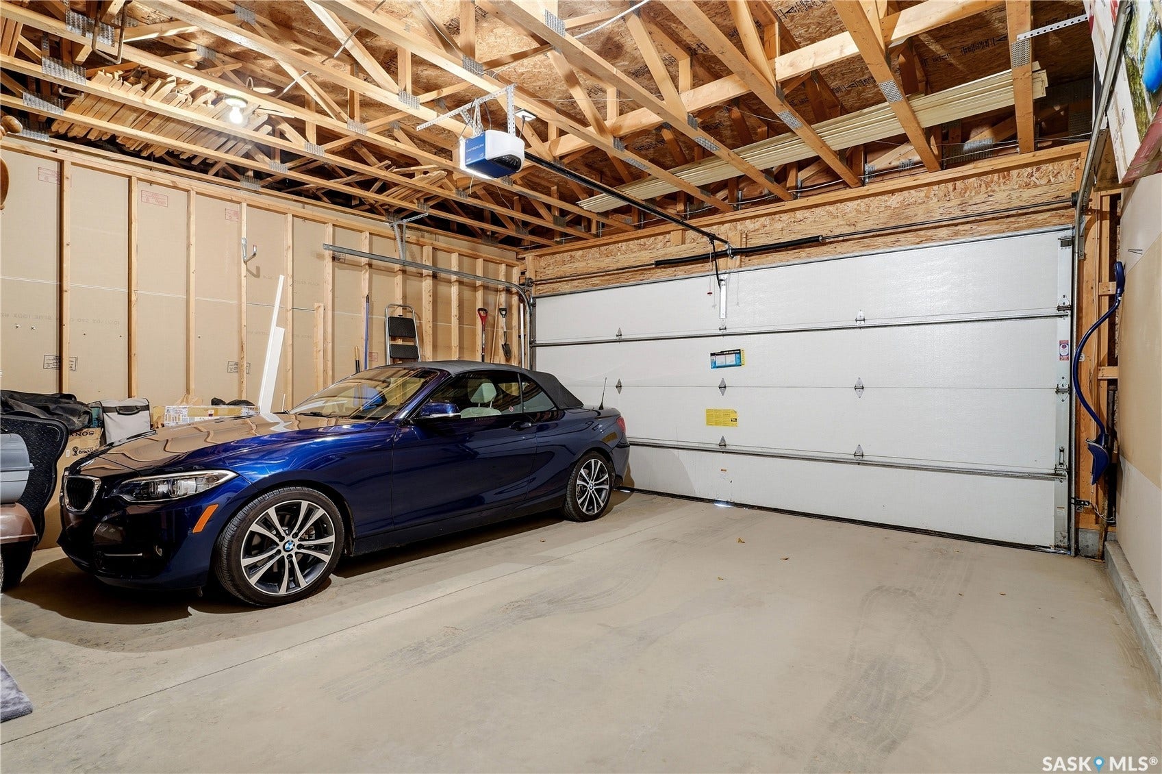 Attached garage with exposed wood beam ceiling, concrete flooring, and an overhead garage door