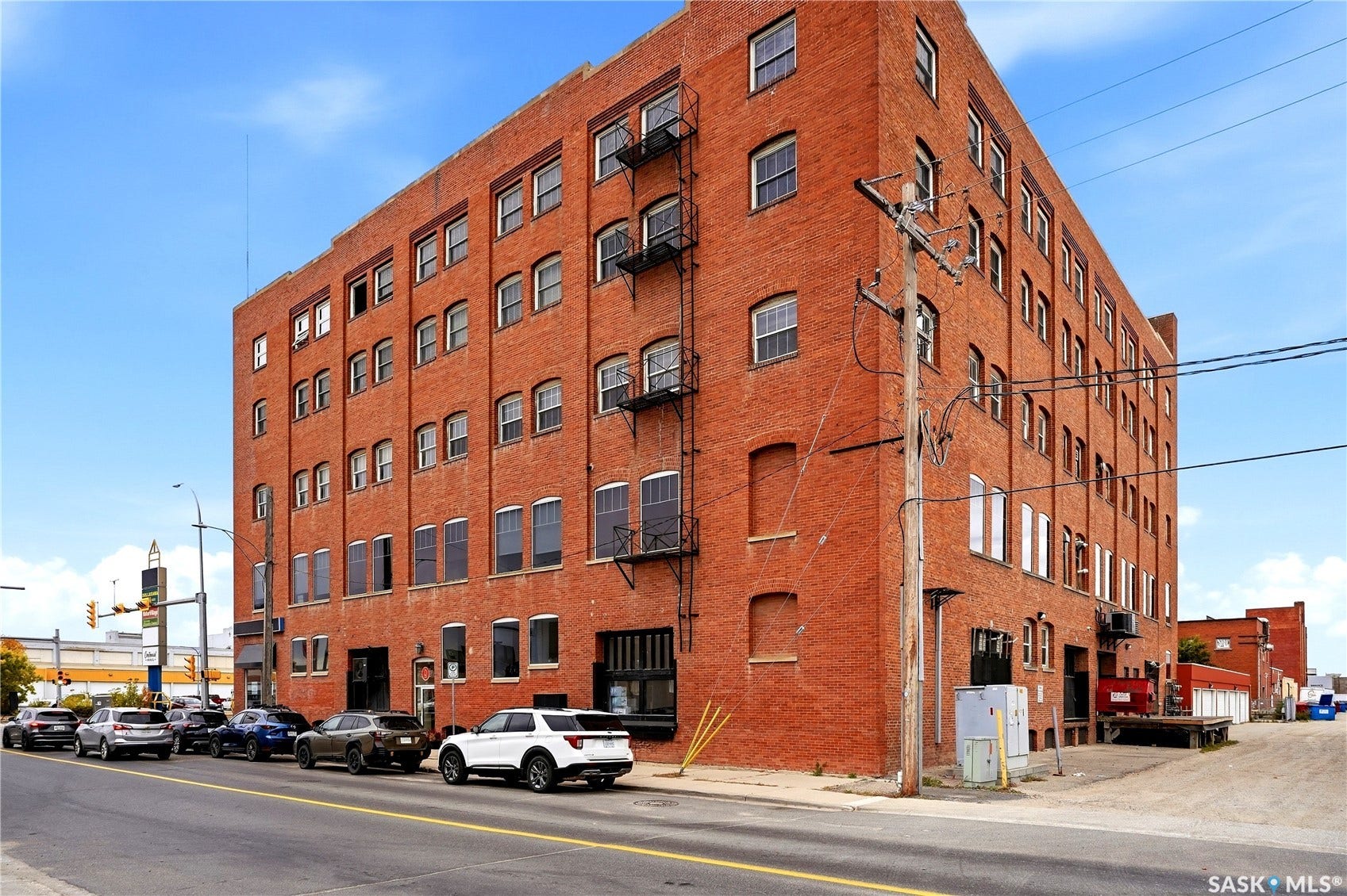 Multi-story brick building with multiple windows, street-facing facade, and multiple fire escapes
