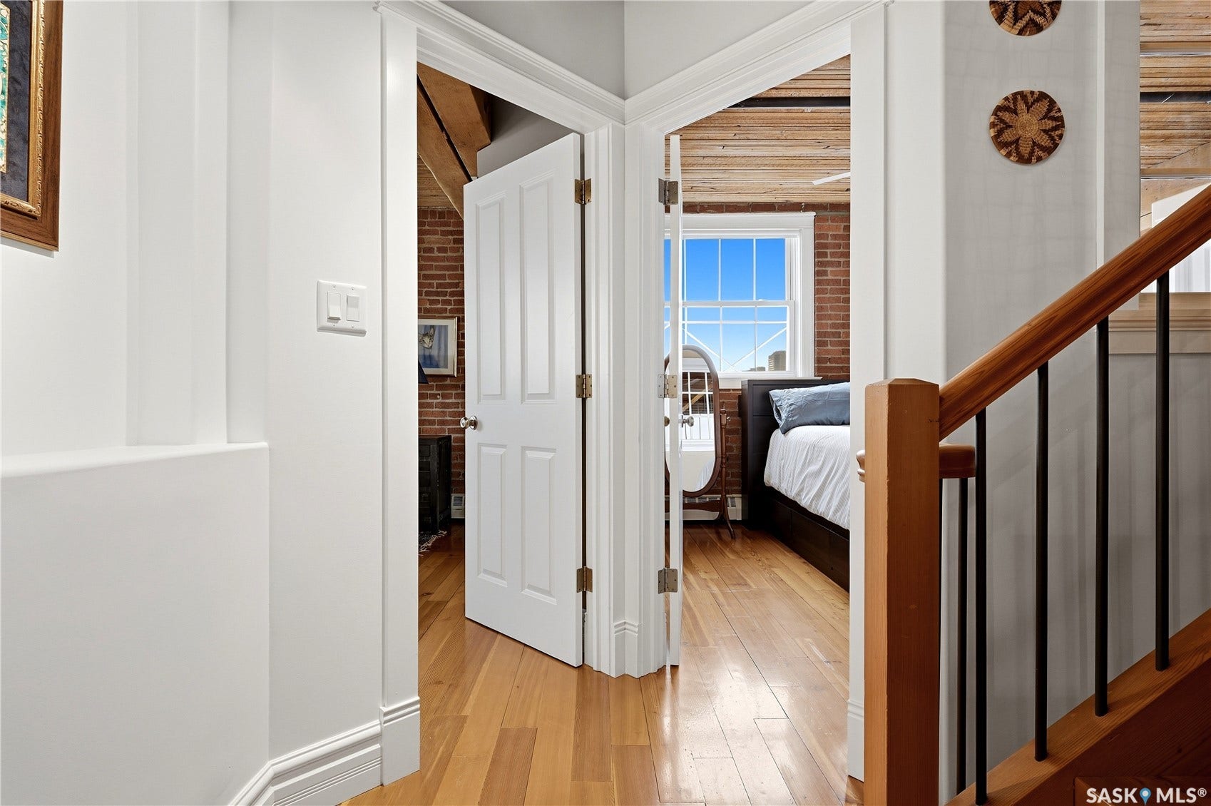 Hardwood flooring, exposed brick wall, wood ceiling, built-in window, wood staircase with metal balusters
