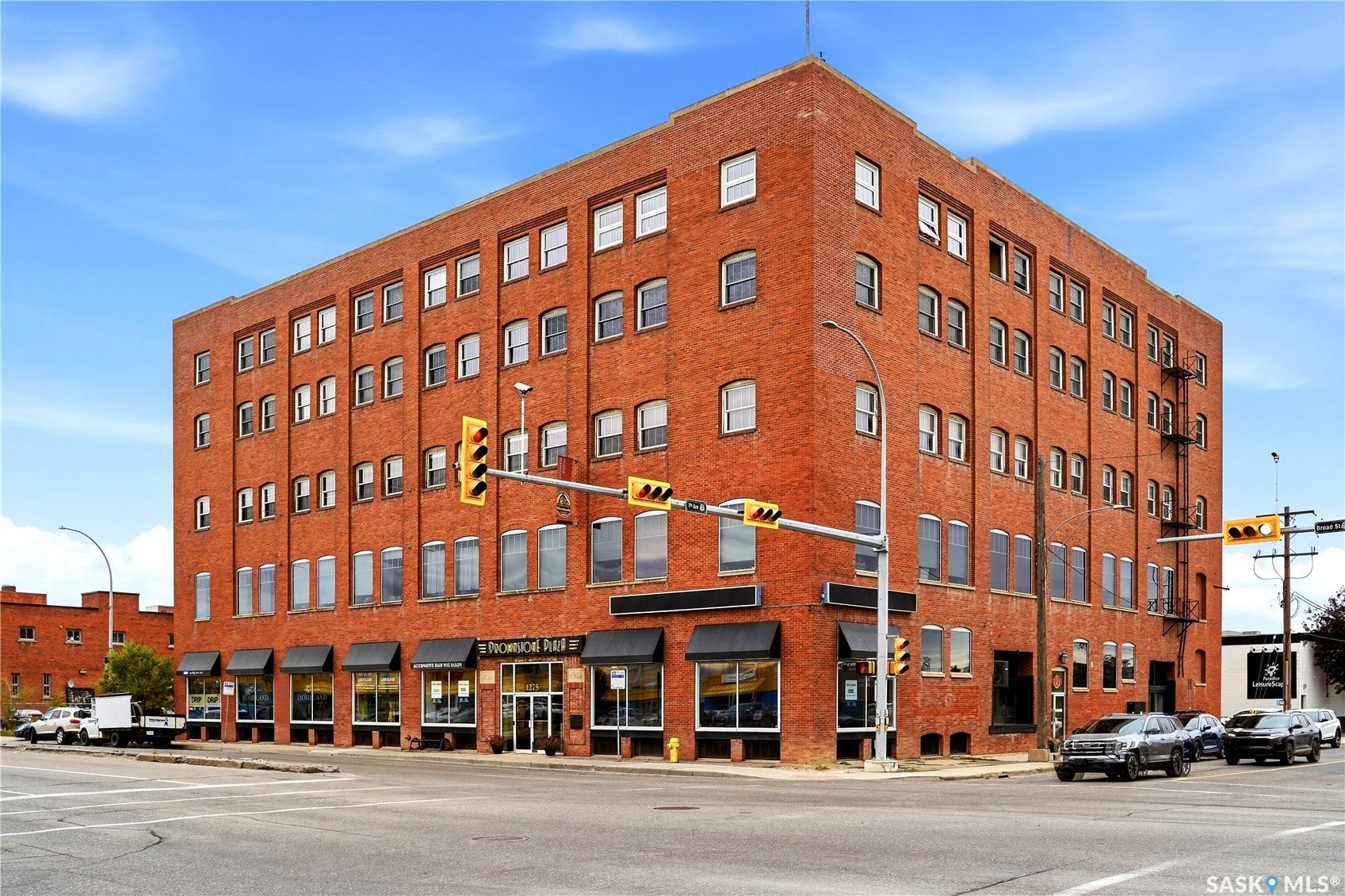 Brick facade building with multiple levels, featuring numerous windows and ground-level storefronts