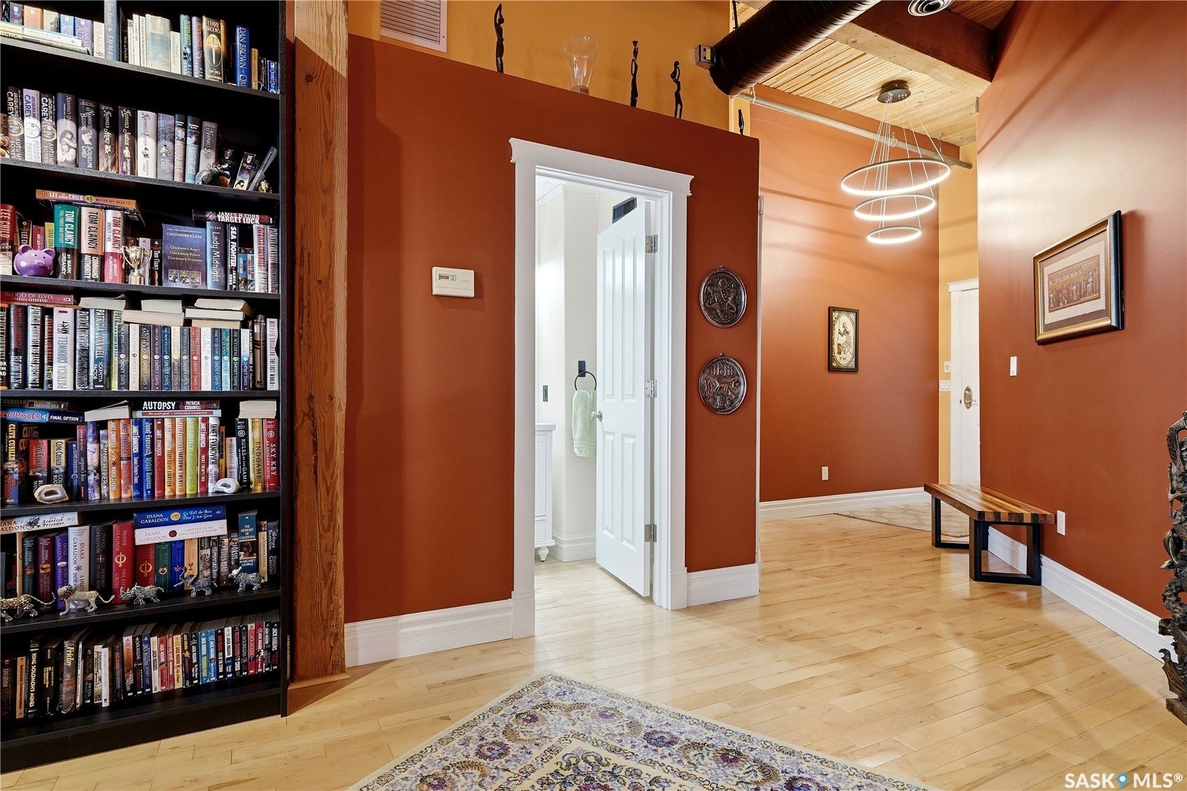 Hardwood flooring with a herringbone pattern, exposed wooden ceiling beams, and a built-in bookcase