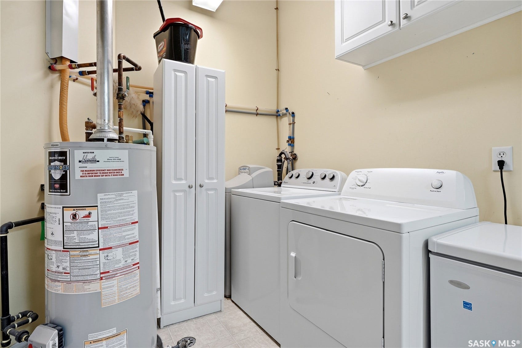 Laundry area featuring a water heater, white cabinetry, and overhead storage