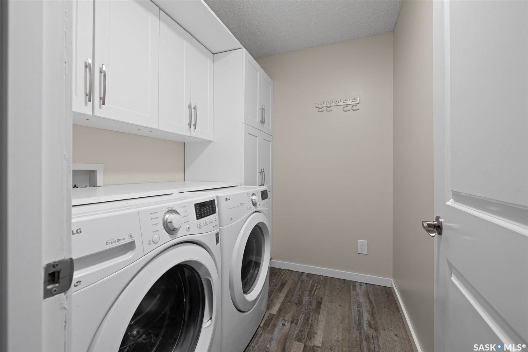 Dedicated laundry area featuring abundant white cabinetry, a built-in countertop, and wood-finish flooring