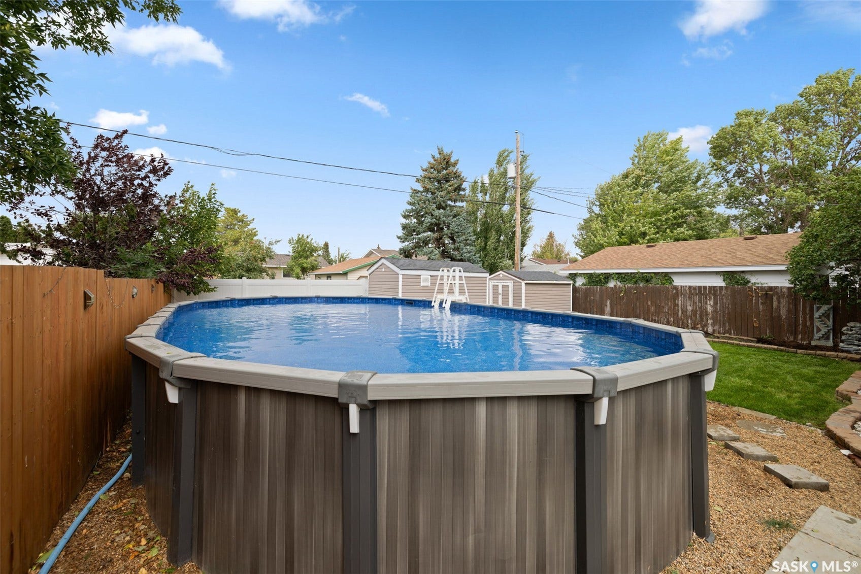 Above-ground pool with ladder access, surrounded by a wood-paneled fence