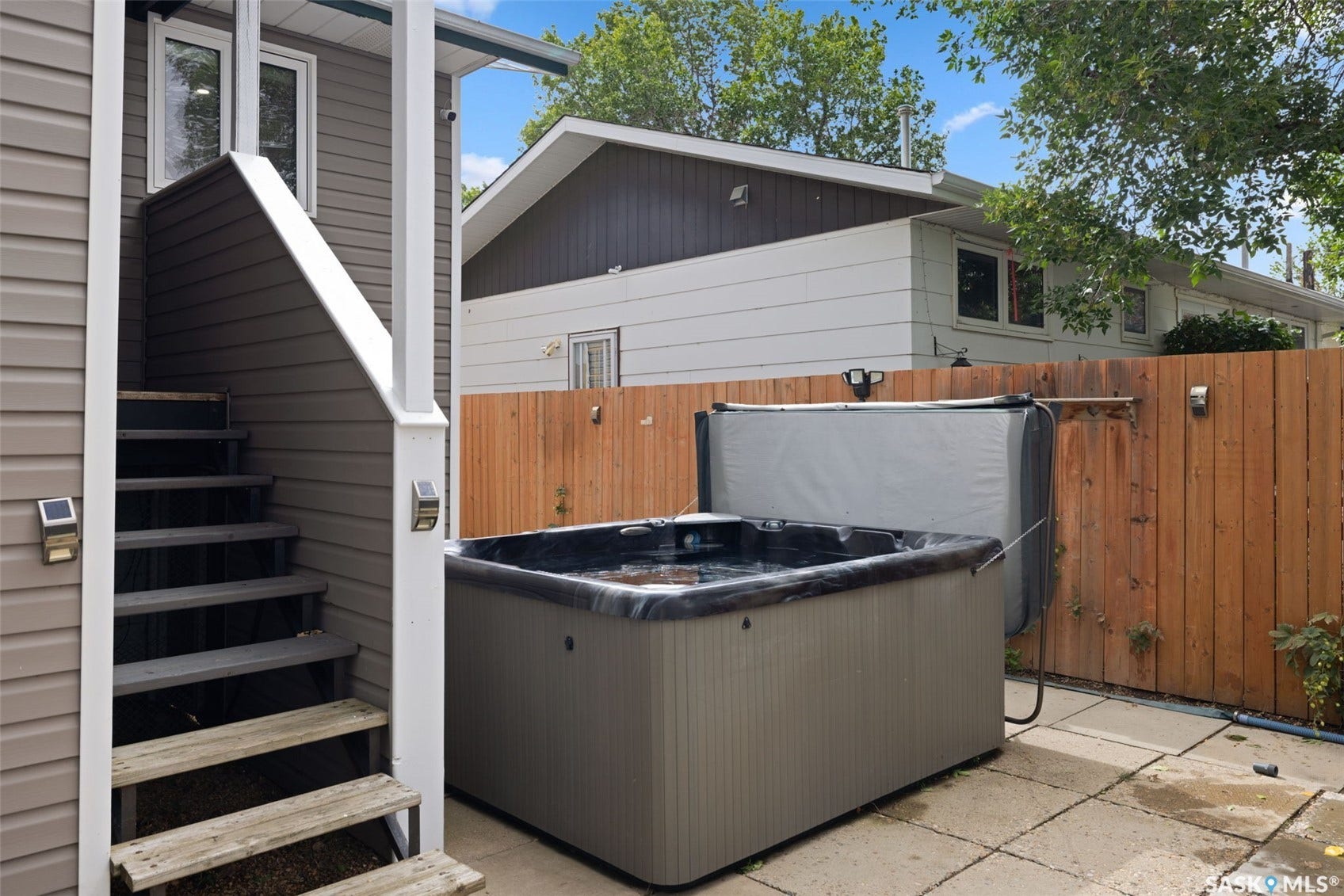 Patio area featuring a hot tub, wood privacy fencing, and concrete paver flooring