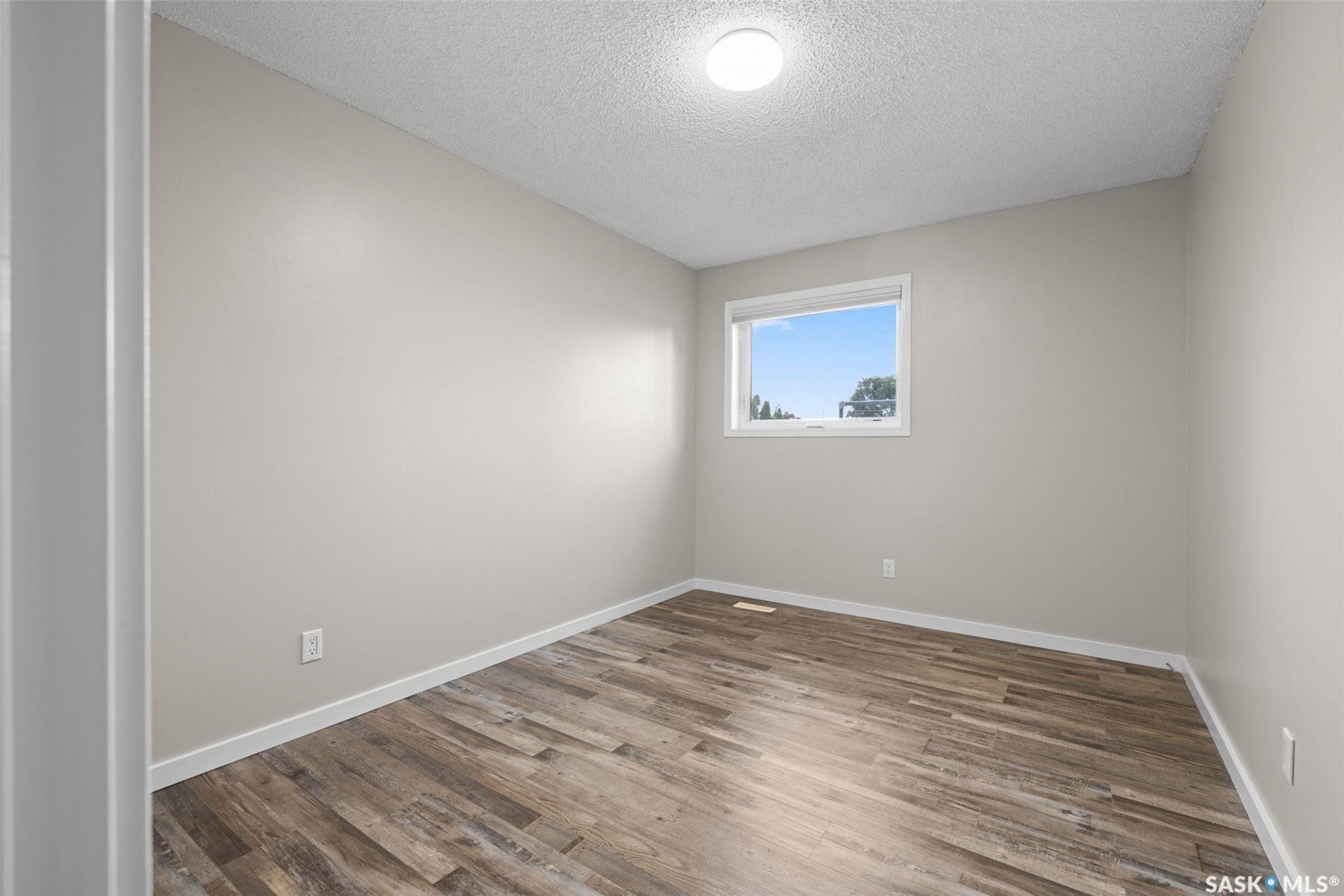 Wood-finish flooring, neutral wall tones, and a window with white trim