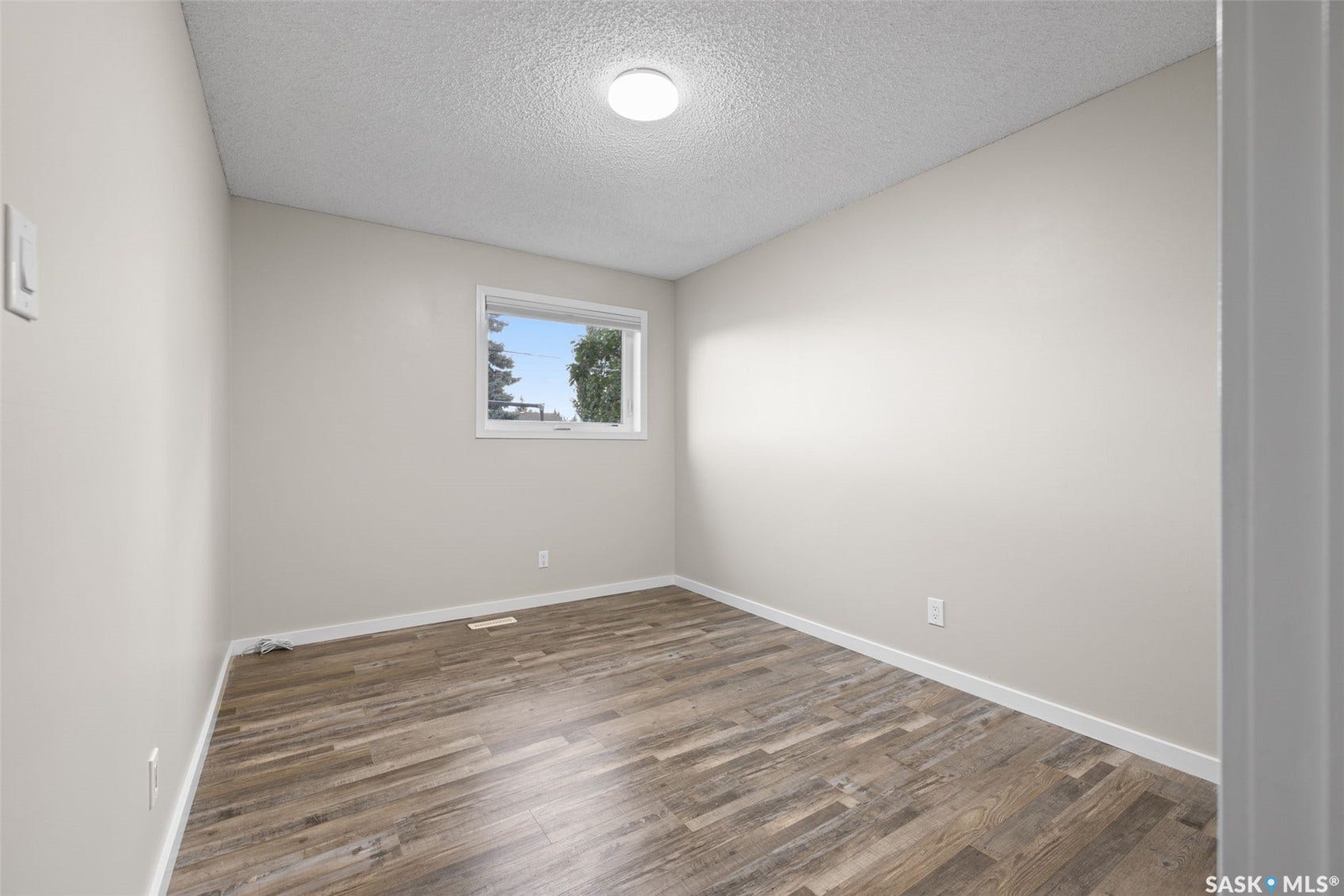Wood-finish flooring, neutral wall paint, single window, and flush mount lighting