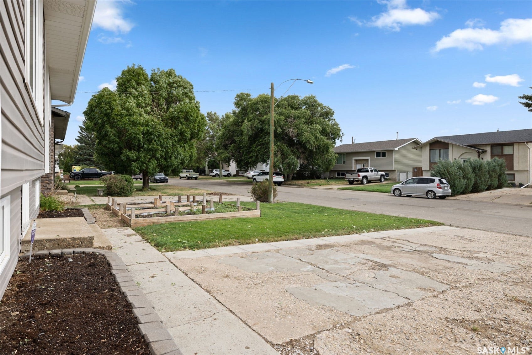 Siding exterior with stone accent, front walkway, established landscaping, and raised garden beds