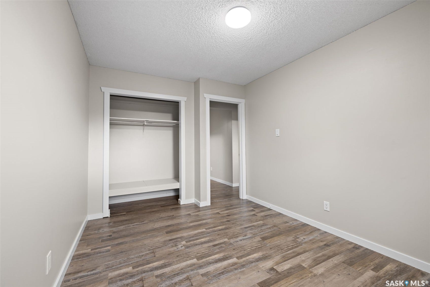 Wood-finish flooring, neutral wall tones, and overhead flush mount lighting