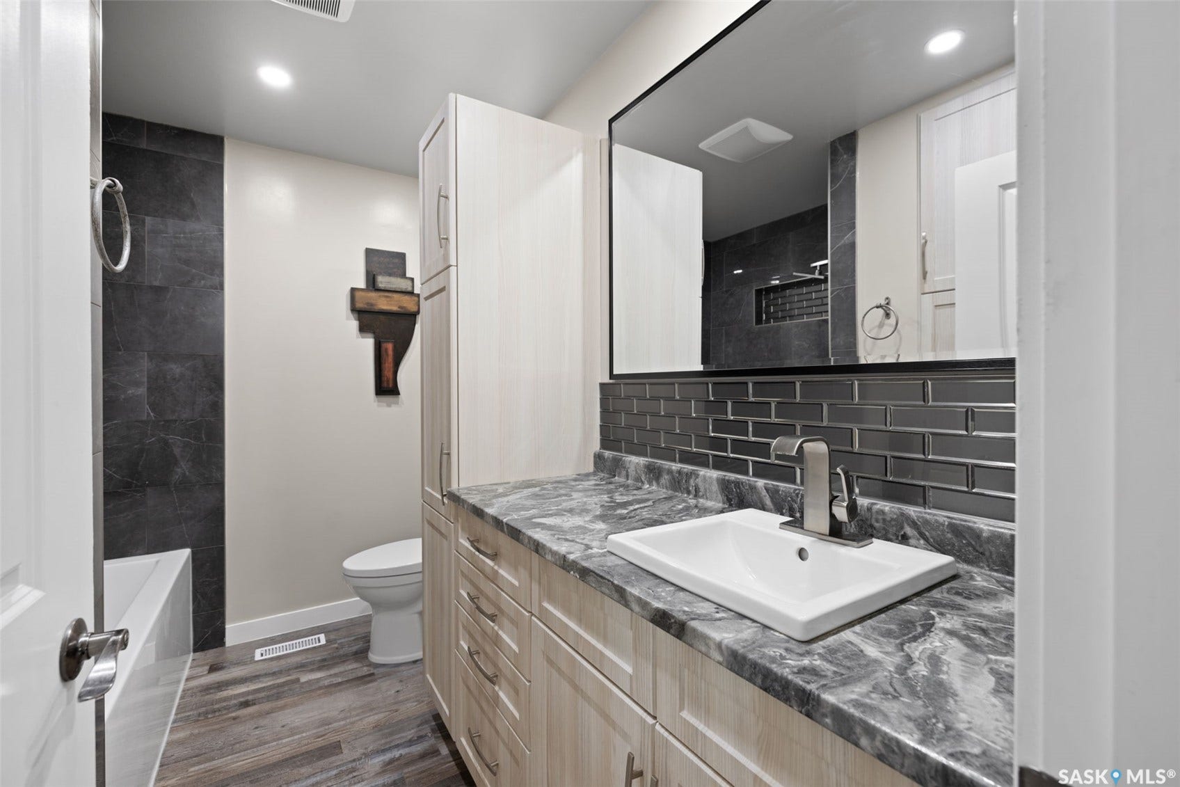 Wood-finish flooring with a rectangular undermount sink, brushed nickel faucet, and glossy subway tile backsplash