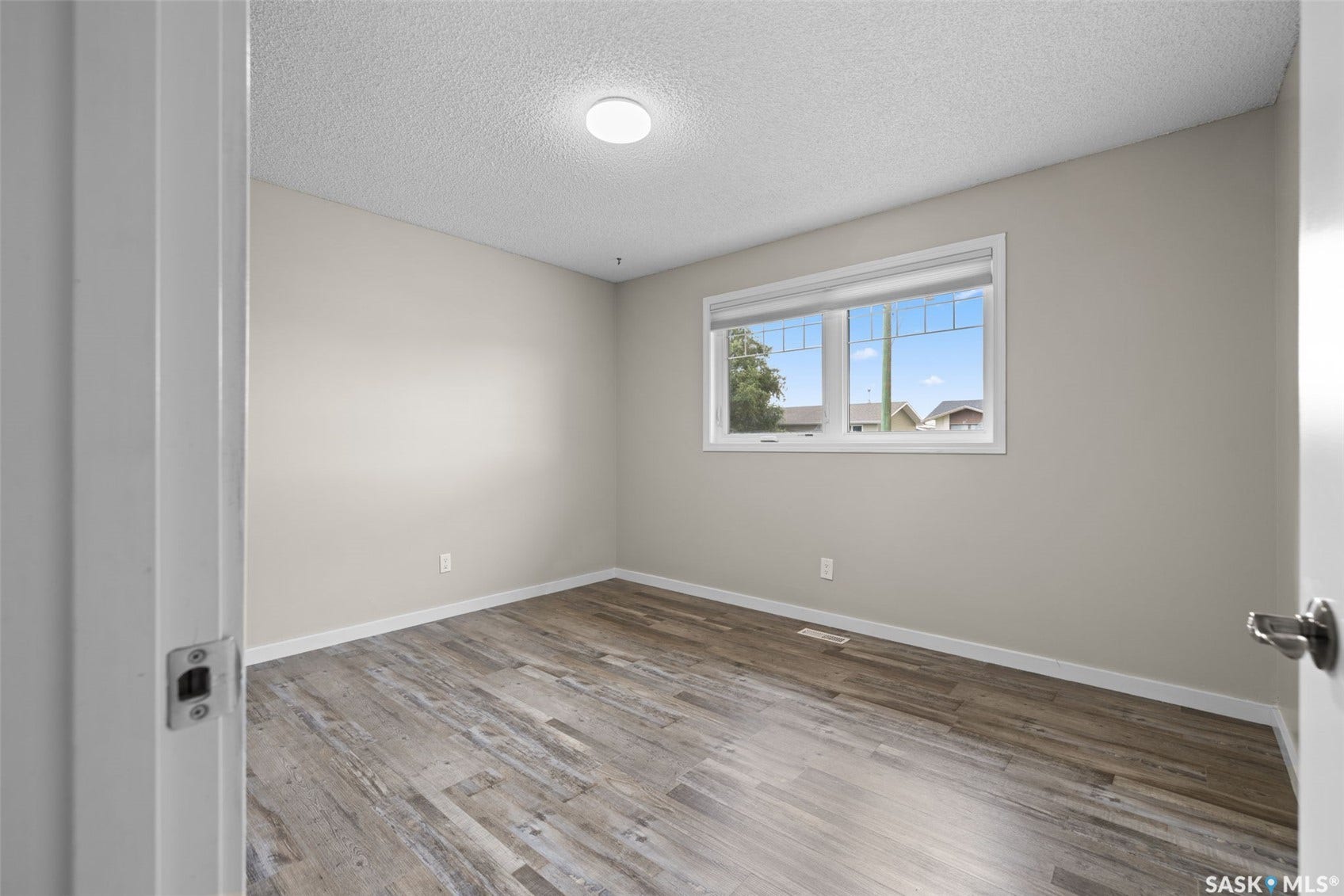 Recessed ceiling light, wood-finish flooring, and a window with white trim