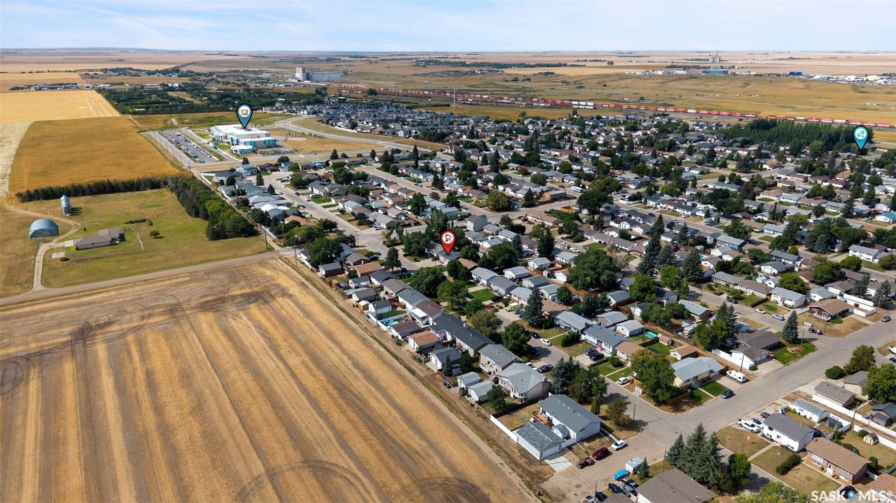 Aerial perspective of a residential neighborhood with cultivated fields and a commercial structure