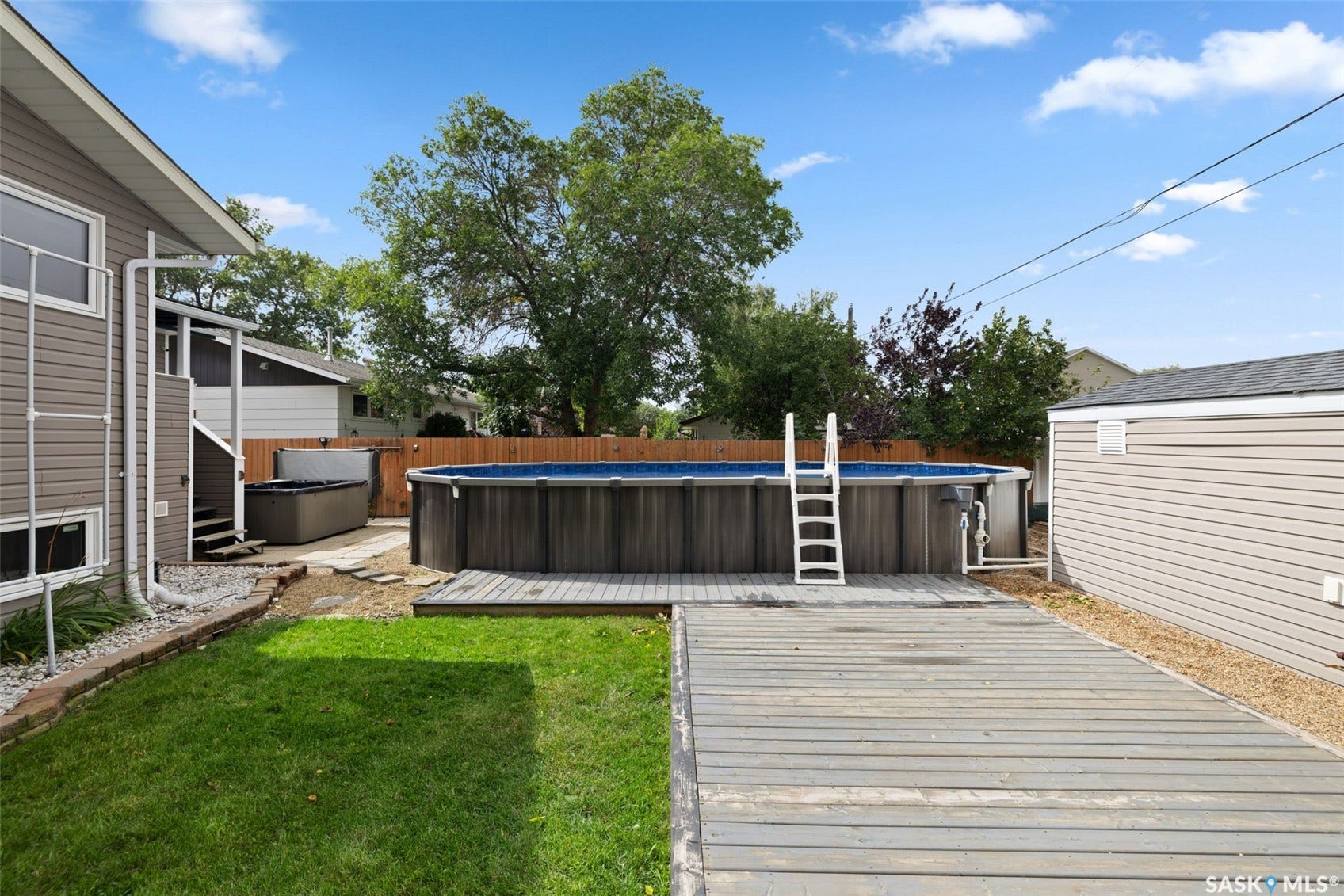Expansive backyard featuring a manicured lawn, above-ground pool, and a hot tub