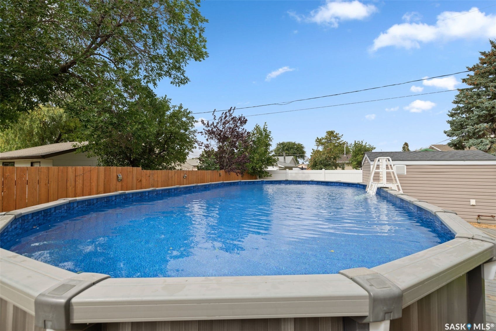 Above-ground swimming pool with a liner, wooden privacy fence, and an adjacent storage shed