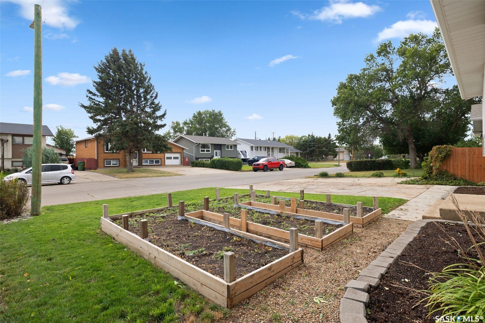 Manicured lawn with two raised garden beds and a stone-edged planter