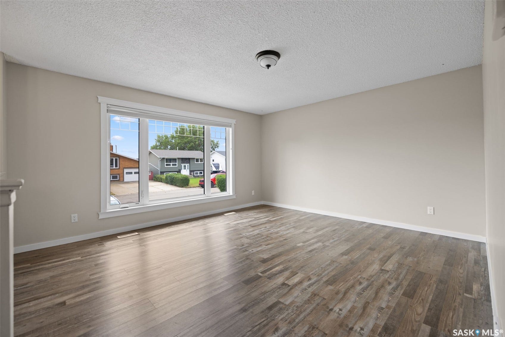 Spacious room featuring wood-finish flooring and a large picture window with white trim