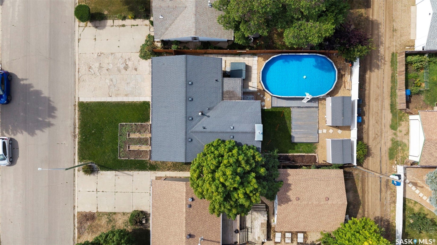 Property featuring a gray shingle roof, a front lawn with a planting bed, and a back yard with an oval above-ground pool