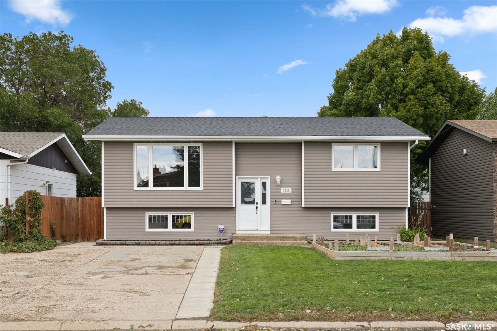 Split-level residence featuring gray siding, white trim, and a dark shingle roof