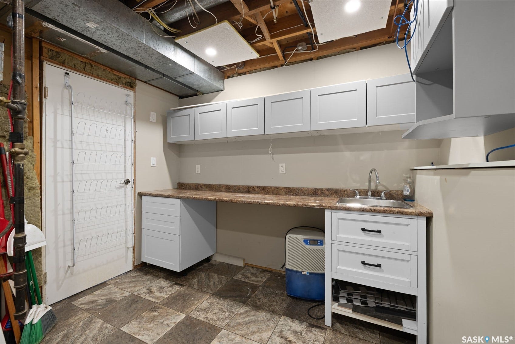 White shaker-style cabinetry with matte black hardware, stainless steel sink, and a laminate countertop