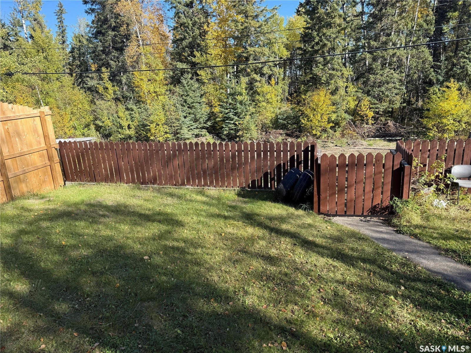 708 Studer Street, La Ronge SK S0J 1L0 Fenced backyard with natural landscaping and a brown picket fence