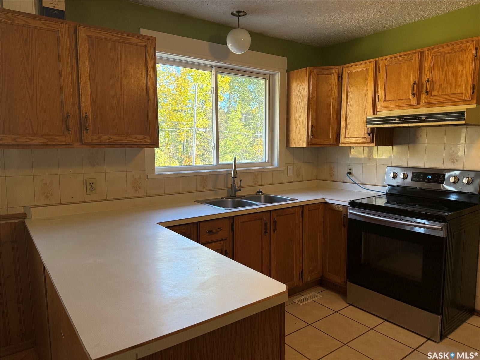 708 Studer Street, La Ronge SK S0J 1L0 Kitchen with wood-finish cabinetry, white countertops, a stainless steel electric range, and a dual basin sink