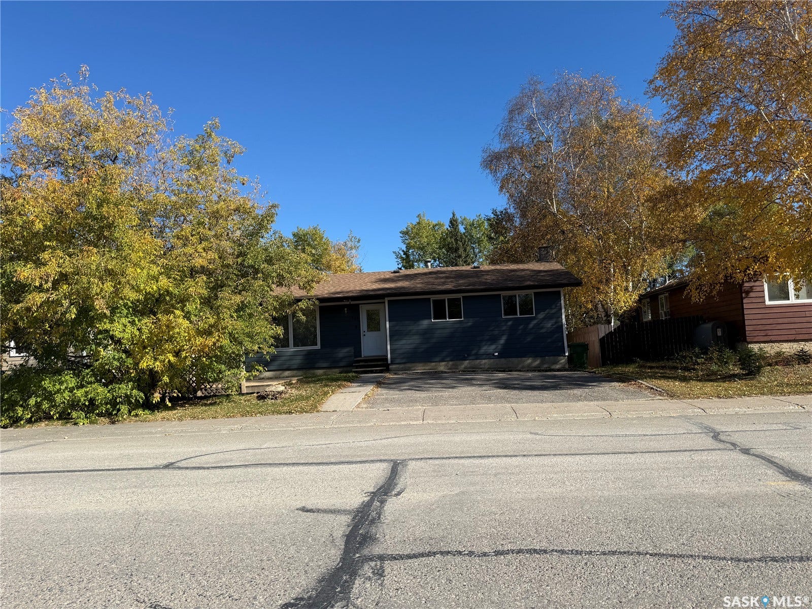 708 Studer Street, La Ronge SK S0J 1L0 Single-story residence with dark blue siding, a brown shingle roof, and white-framed windows