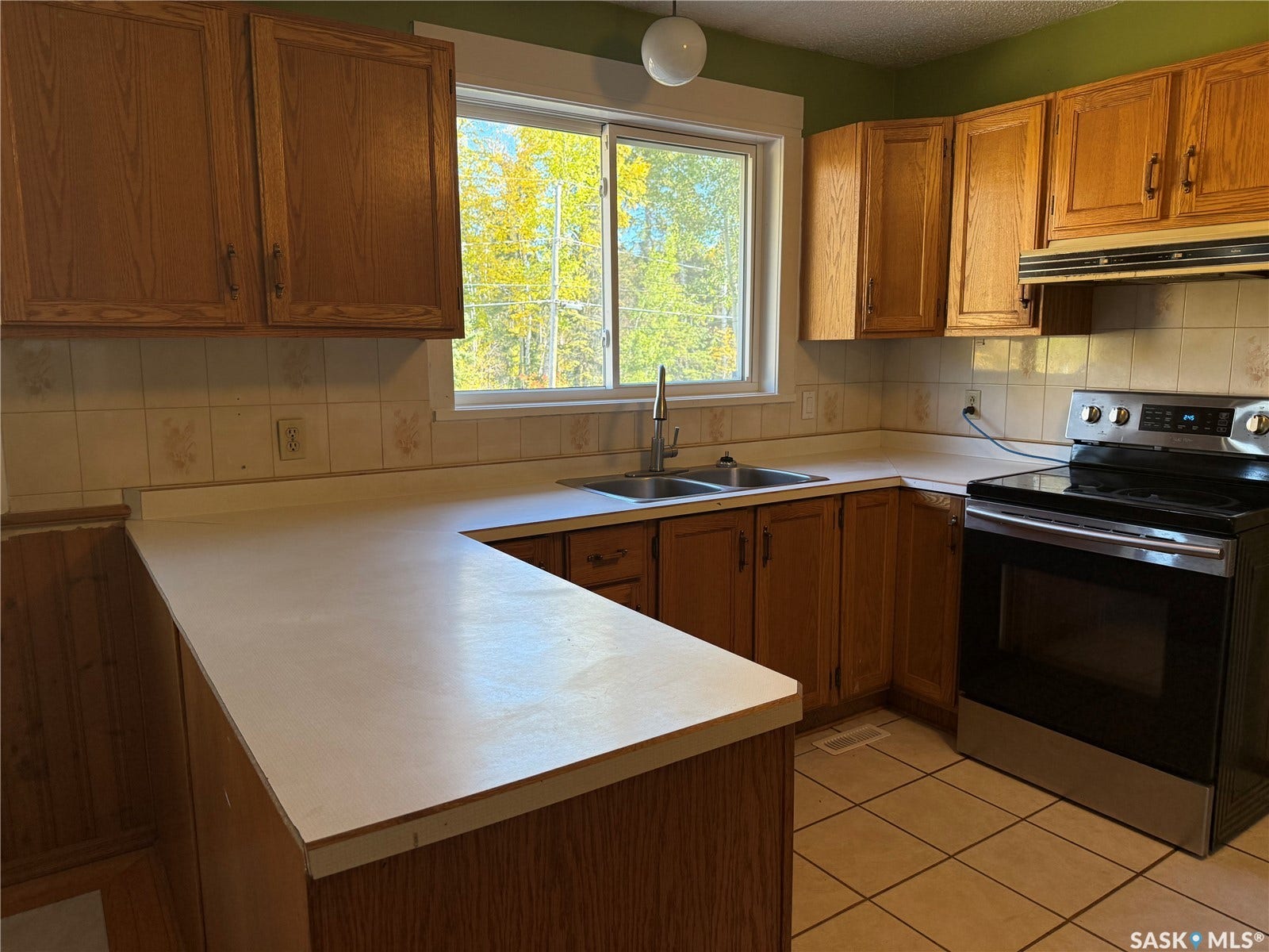 708 Studer Street, La Ronge SK S0J 1L0 Kitchen with wood-finish cabinetry, tile flooring, stainless steel range, and a dual-basin sink