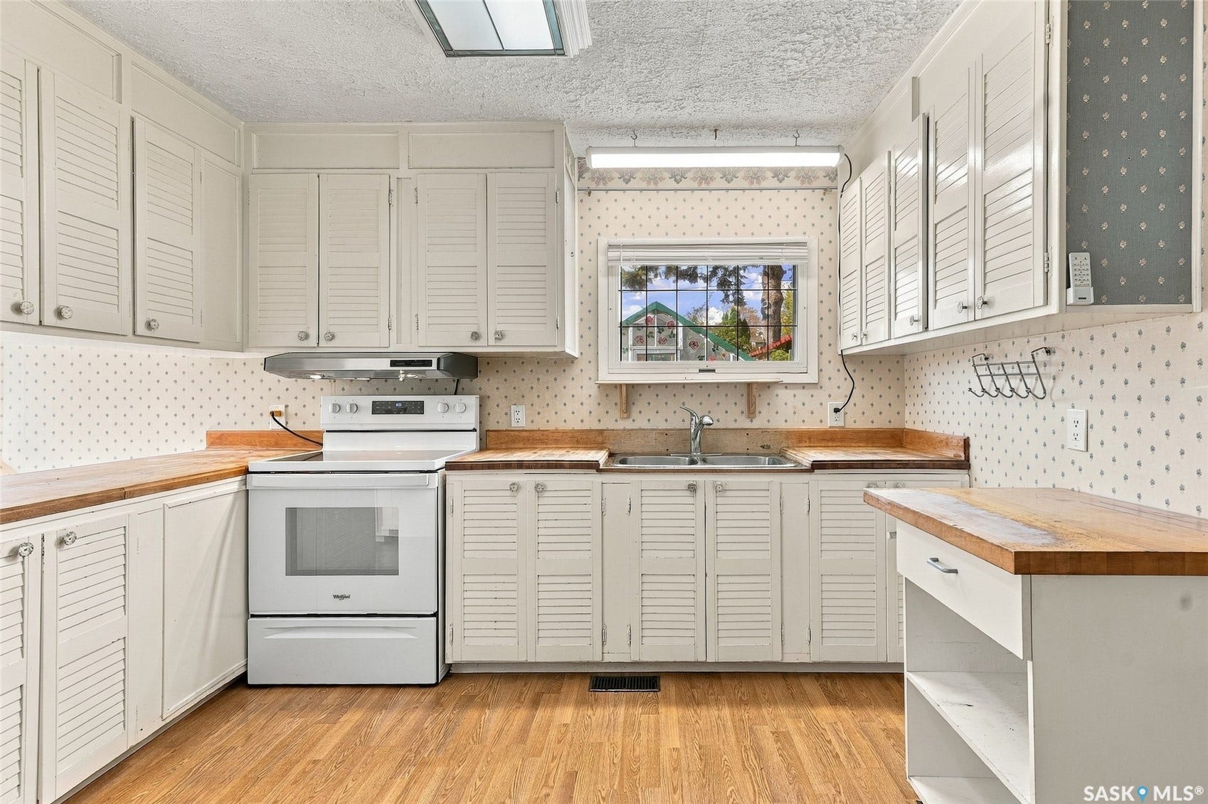 Kitchen with wood-finish flooring, white cabinetry, a built-in oven range, and wood countertops