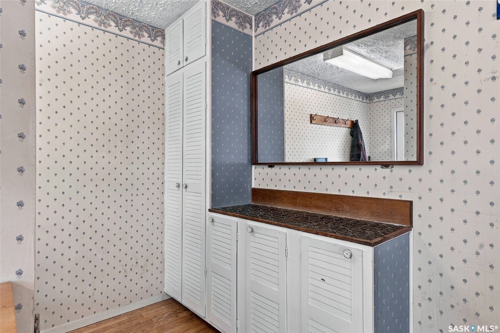 Built-in cabinetry with louvered doors, wood-finish countertop, and a framed wall mirror