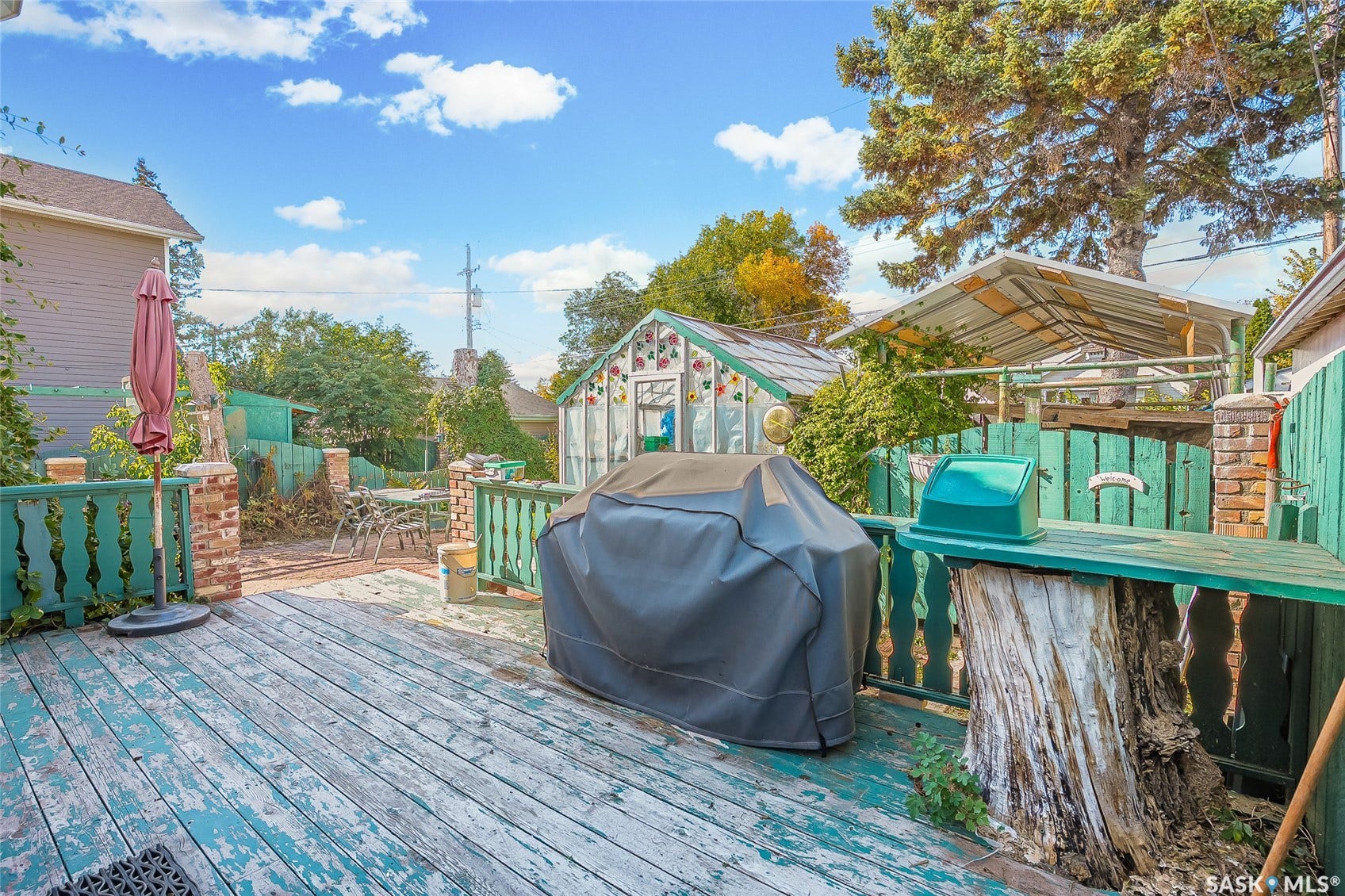 Expansive wood deck with baluster railing, brick pillars, and a built-in wood stump bar