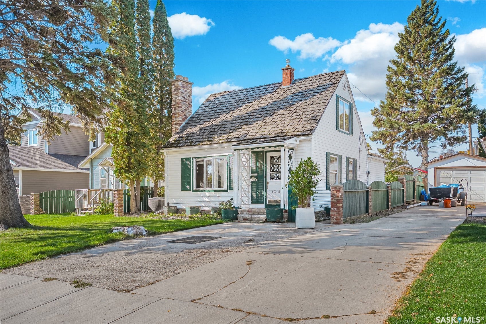 White exterior with green shutters, a gabled roof, and an attached chimney