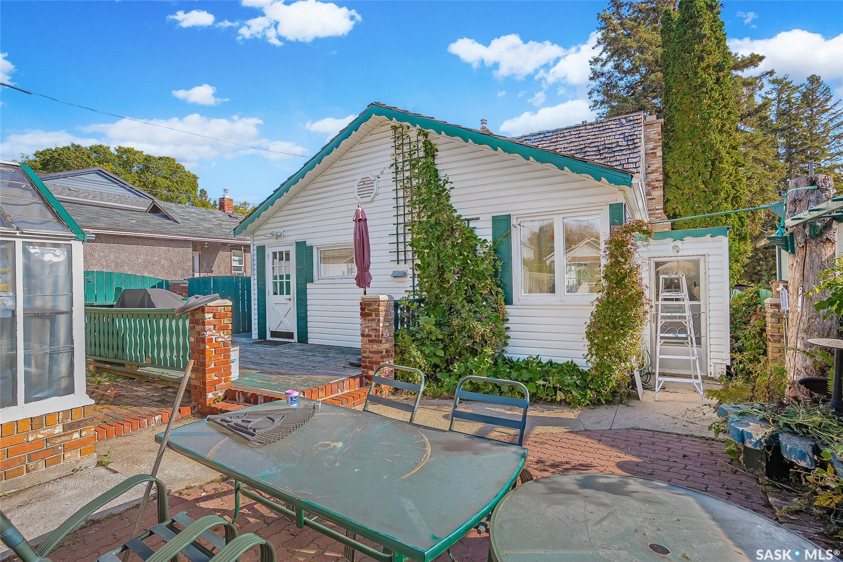 Exterior featuring white siding, green-trimmed shutters, and a prominent chimney