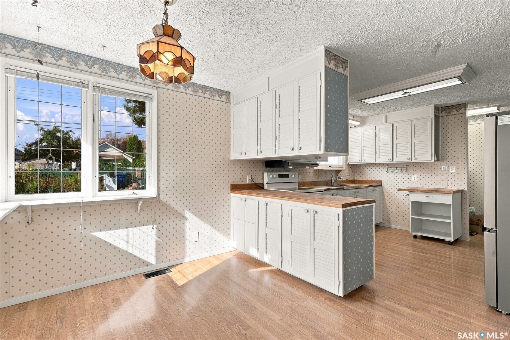 Kitchen featuring wood-finish flooring, white cabinetry, wood-look countertops, and a window with exterior views