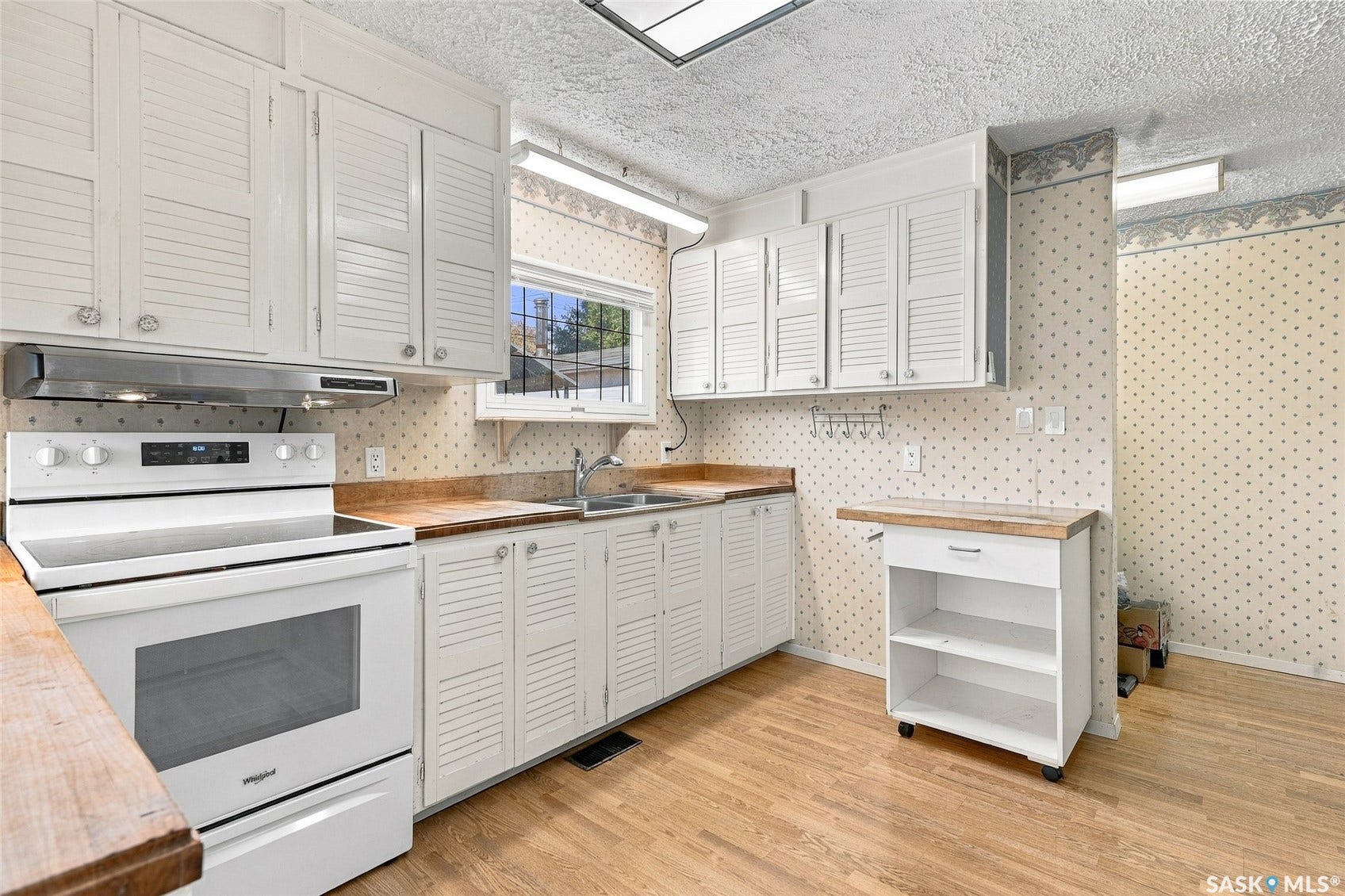Kitchen featuring white cabinetry, wood-finish countertops, and wood-finish flooring