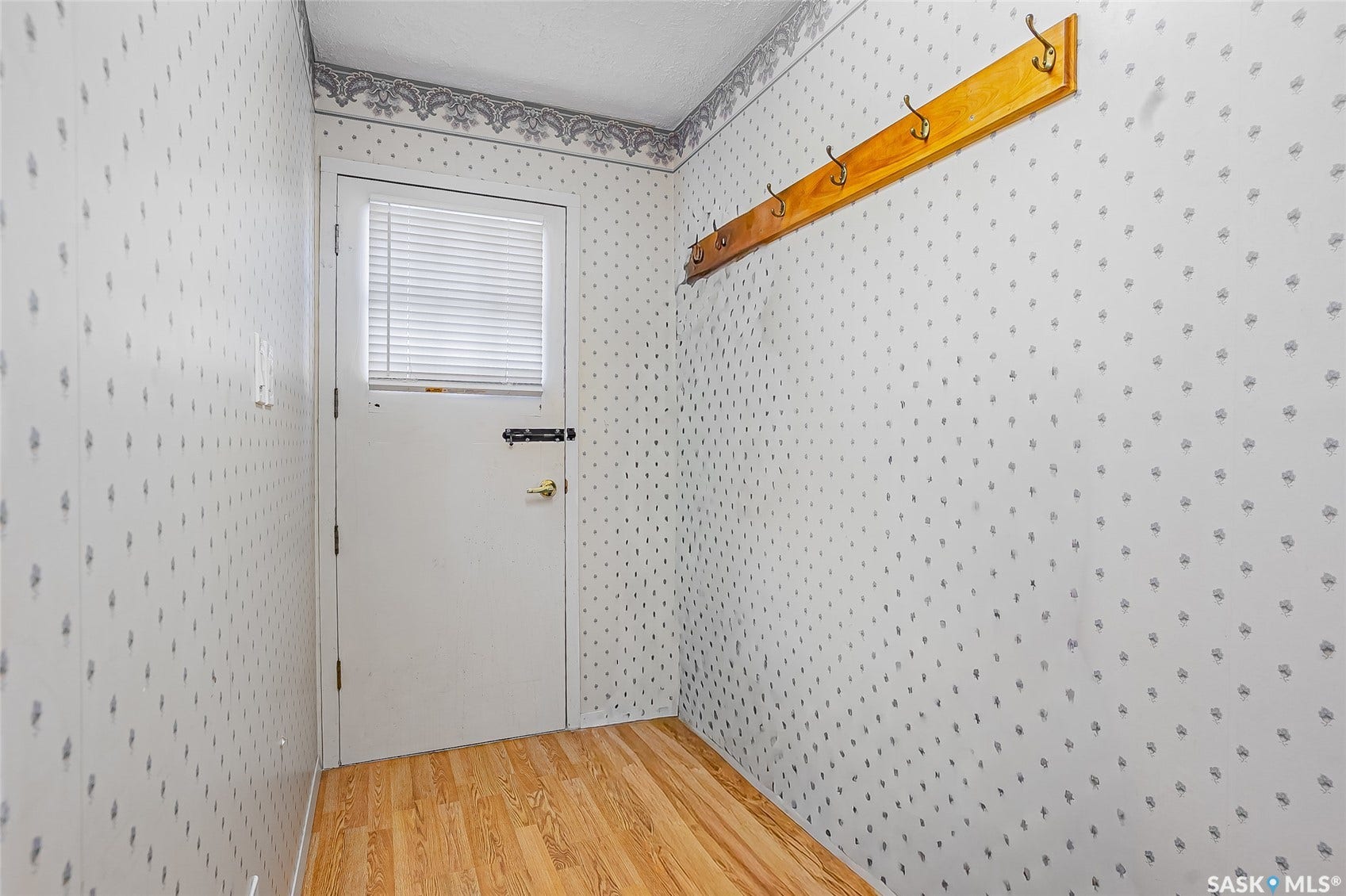 Wood-finish flooring with a white door featuring an integrated window blind