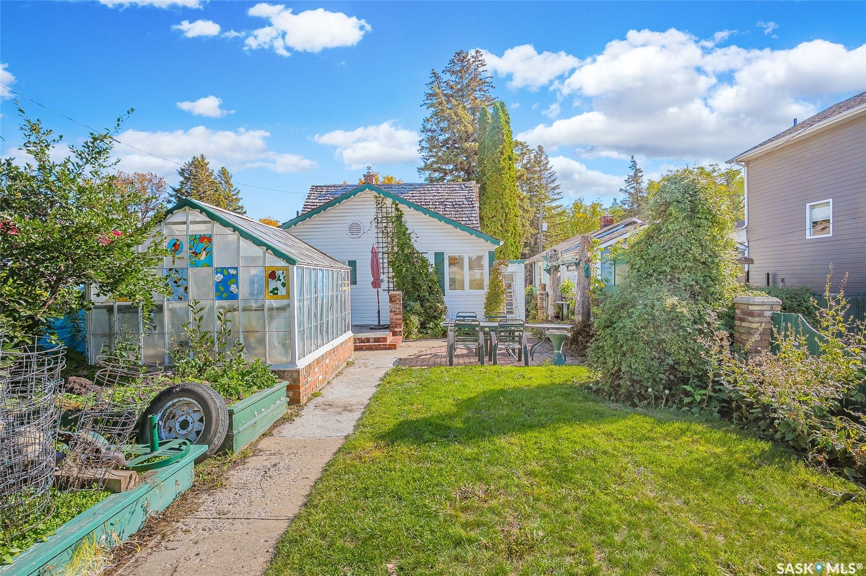 Expansive green lawn, established landscaping, and two distinct greenhouses