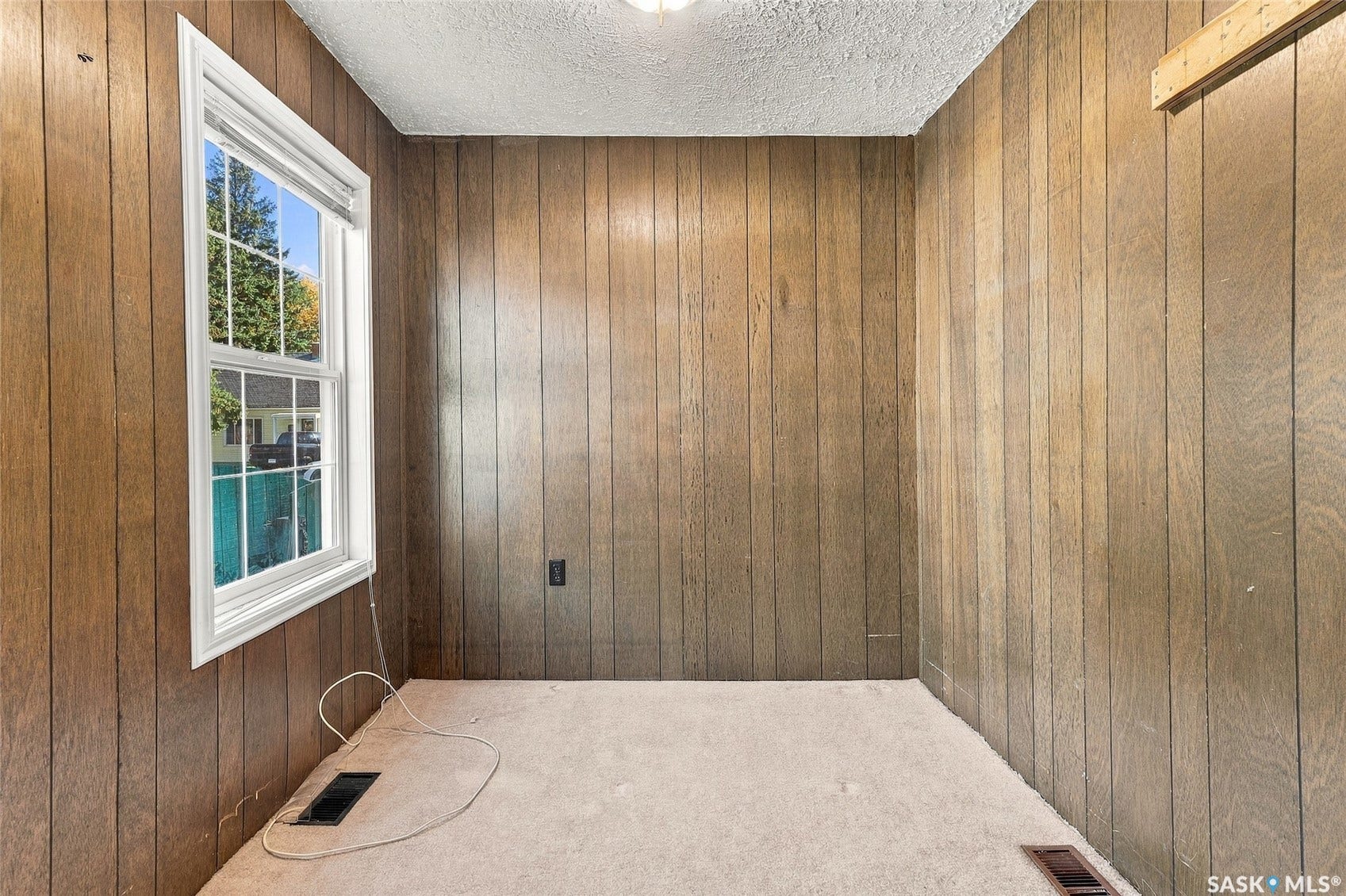 Vertical wood paneling, white window trim, and a textured ceiling