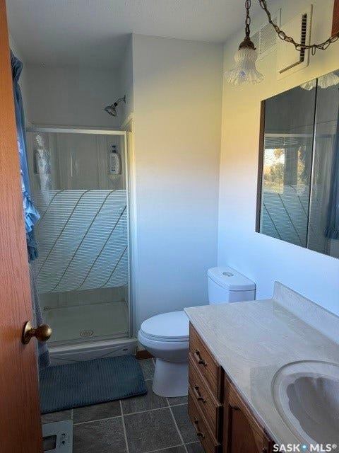Shower enclosure with clear glass doors, single vanity with wood-finish cabinetry, integrated sink, and a framed mirrored medicine cabinet