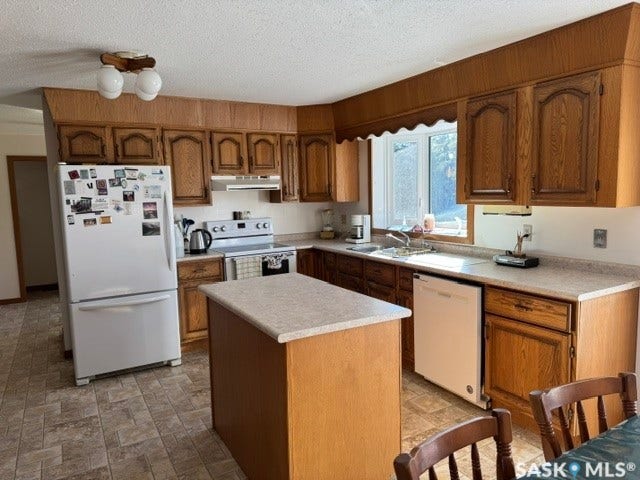 Kitchen featuring wood-finish cabinetry, tile flooring, and a center island with a light-toned countertop