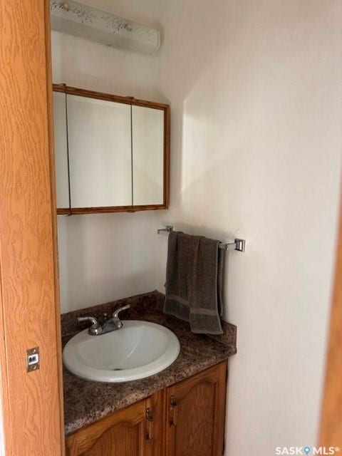 Vanity with wood-finish cabinetry, integrated sink, and patterned countertop