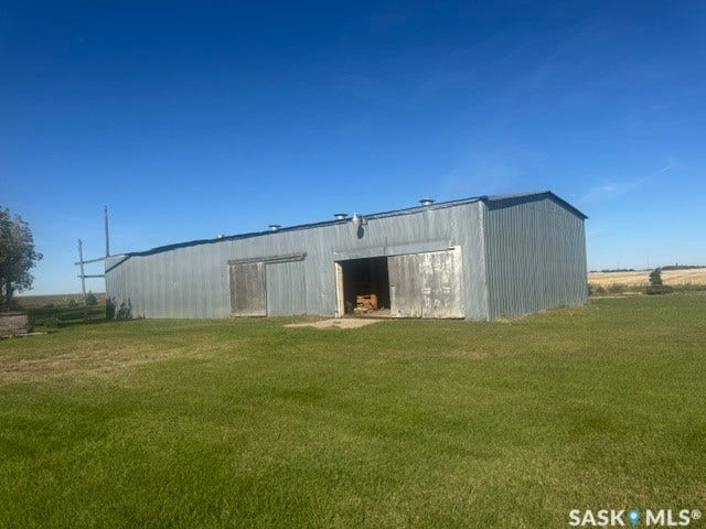 Metal-clad outbuilding with a pitched roof, featuring multiple access doors and a large open entry
